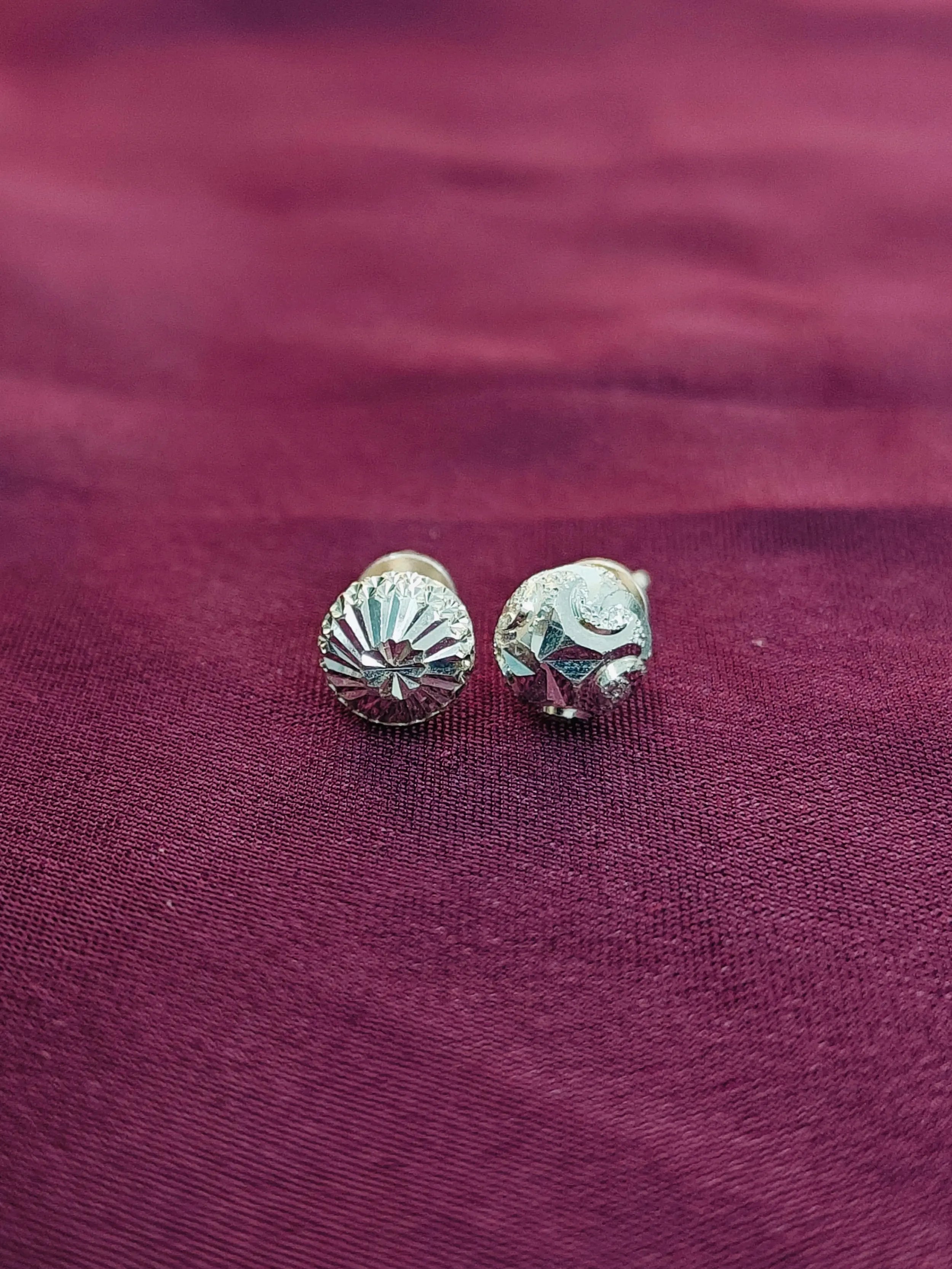 Silver shell-shaped earrings on a purple fabric background